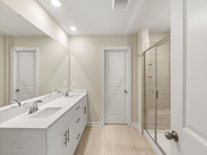 The primary bathroom boasts a dual-sink vanity and modern walk-in shower.
