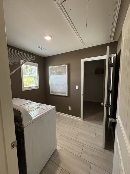 A cozy laundry room with modern appliances, tiled floor, and neutral walls, perfect for efficient home care tasks.