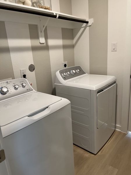 A sleek laundry room featuring modern appliances, striped wall accents, and practical shelving for organization. A sleek laundry room featuring modern appliances, striped wall accents, and practical shelving for organization.
