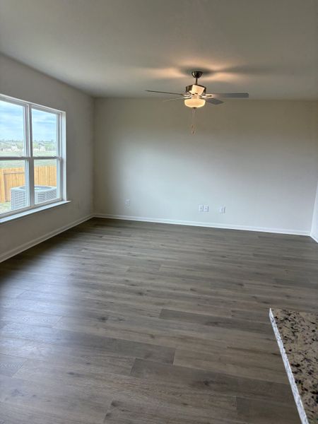 An airy living space with wood flooring, a ceiling fan, and abundant natural light.