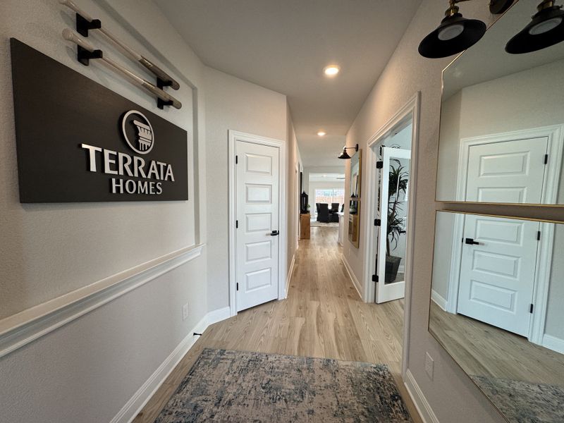 A sleek hallway with light wood flooring, elegant lighting fixtures, and modern decor by Terrata Homes.