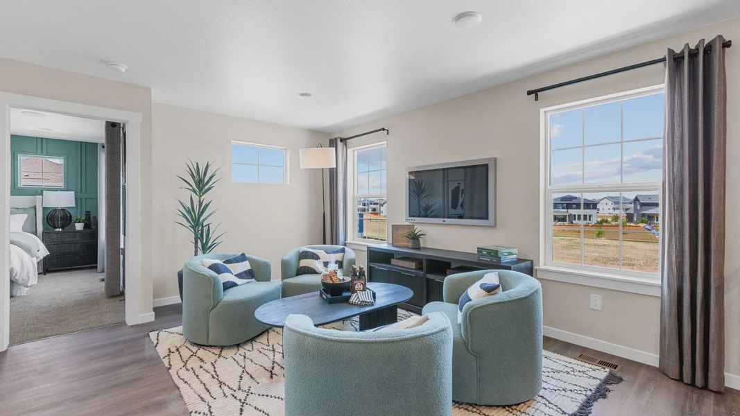 Luxurious living space features plush teal seating, expansive windows, and premium wood floors in Timnath Lakes. Luxurious living space features plush teal seating, expansive windows, and premium wood floors in Timnath Lakes.