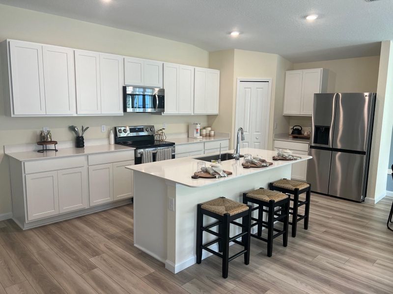 Modern kitchen with sleek white cabinets, stainless steel appliances, and a spacious island with barstools.
