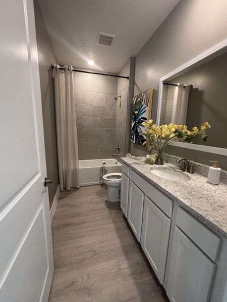 Stylish bathroom with white cabinetry, granite countertops, and a tub-shower combination.