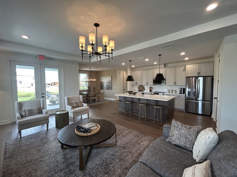 An open-concept living space with cozy seating, a modern kitchen, and elegant lighting fixtures.