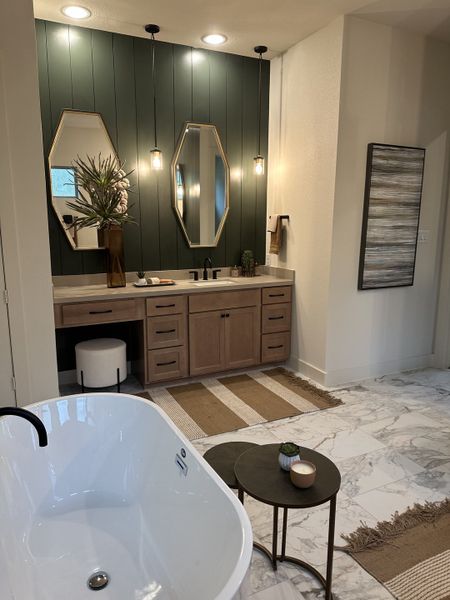 A chic bathroom with a freestanding tub, dual mirrors, modern lighting, and elegant decor accents.
