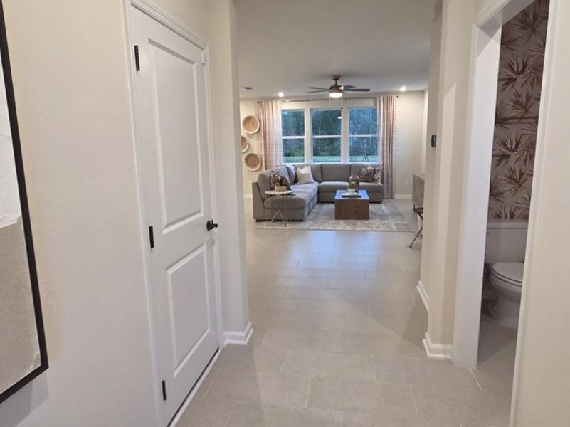 A cozy living area with a plush sectional, neutral tones, and nature-inspired decor viewed from a bright hallway.