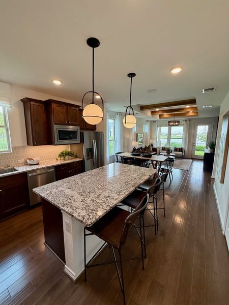 A modern kitchen with granite island, dark wood cabinets, stainless steel appliances, and open living space with ample natural light. A modern kitchen with granite island, dark wood cabinets, stainless steel appliances, and open living space with ample natural light.