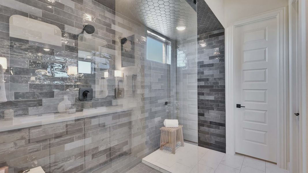 Experience opulence in a shower featuring hexagonal tiles and high-end fixtures in Flora community's modern design.