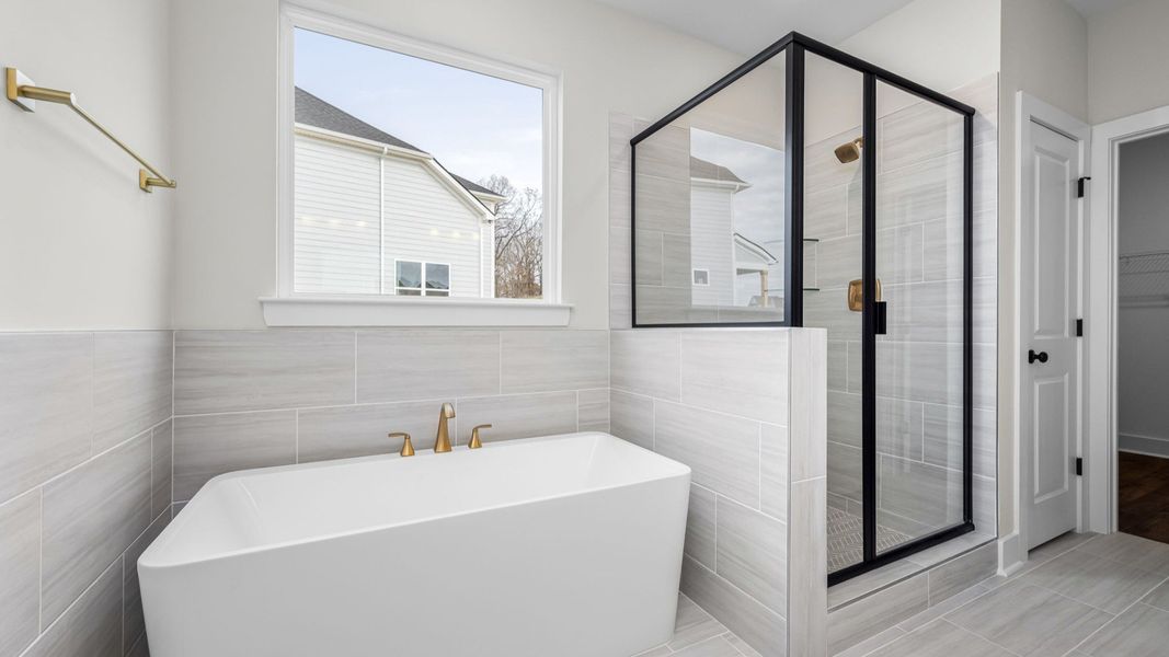 Beautiful primary bathroom with tub and glass enclosed shower Beautiful primary bathroom with tub and glass enclosed shower