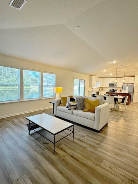 A bright, open living space with a cozy sofa, modern coffee table, and a seamless flow to the dining area and kitchen.