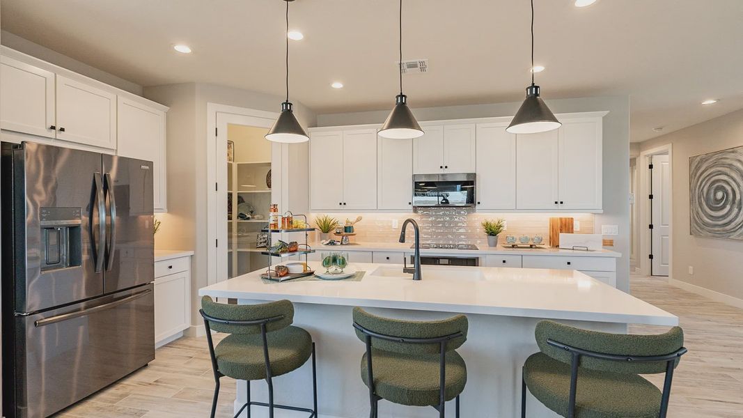 Experience refined elegance with sleek stone countertops and stylish pendant lighting in Sienna Park's kitchen.