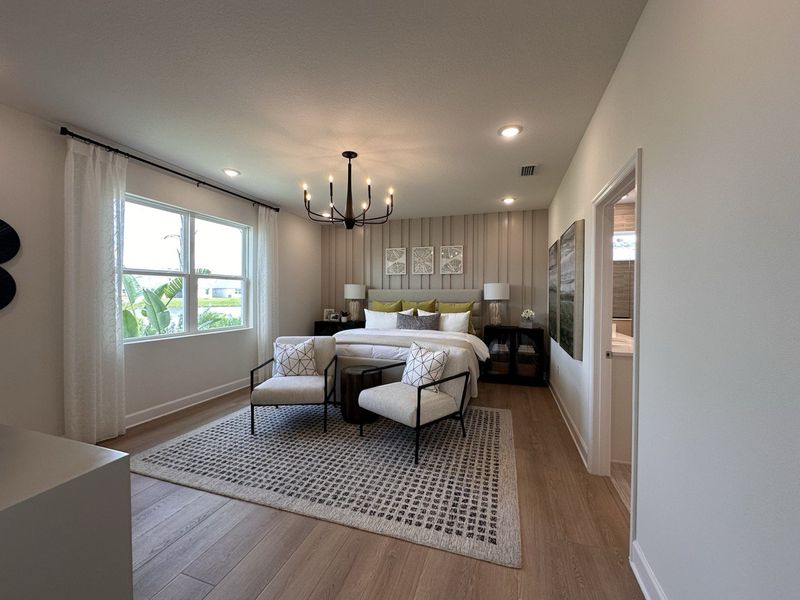 A spacious bedroom with a cozy bed, elegant chandelier, and large window offering natural light.