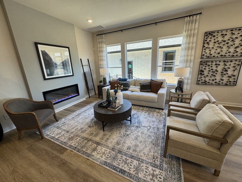 A cozy living room with a sleek fireplace, elegant décor, plush seating, and large windows providing ample natural light.