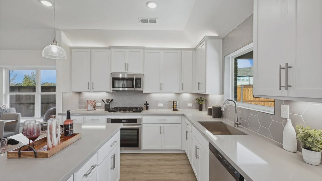 Elegant kitchen features sleek white cabinetry and striking hexagonal backsplash in Bel Air Village.