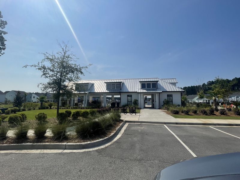 Charming clubhouse with a modern metal roof and landscaped grounds in Homecoming by True Homes (Ravenel, SC).