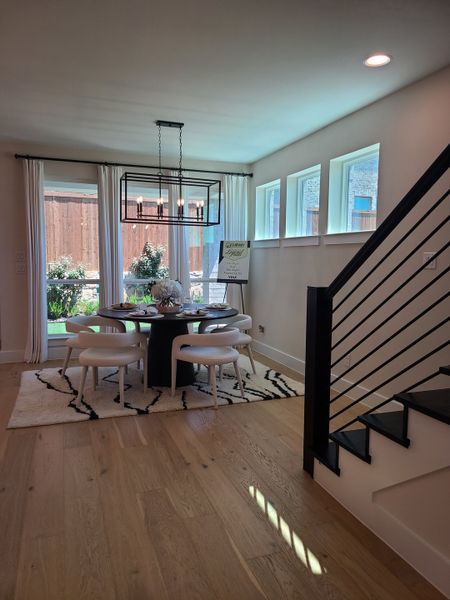 A chic dining area with a modern chandelier, elegant round table, and stylish chairs on a patterned rug. A chic dining area with a modern chandelier, elegant round table, and stylish chairs on a patterned rug.