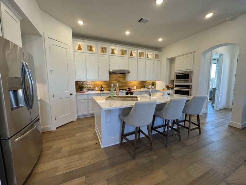 A modern kitchen featuring a large island, sleek appliances, and elegant cabinetry with brass accents. A modern kitchen featuring a large island, sleek appliances, and elegant cabinetry with brass accents.