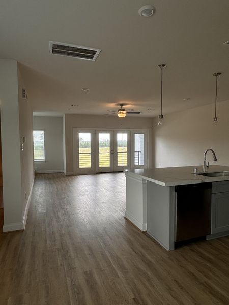 An open-concept living area with wood floors, modern lighting, and large windows offering natural light. An open-concept living area with wood floors, modern lighting, and large windows offering natural light.