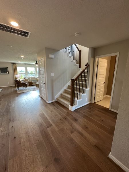 A welcoming interior with rich wood floors, a cozy living area, and a stylish staircase, offering warmth and elegance.