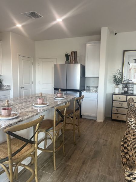 A modern kitchen with a granite island, stylish bar stools, and stainless steel appliances.