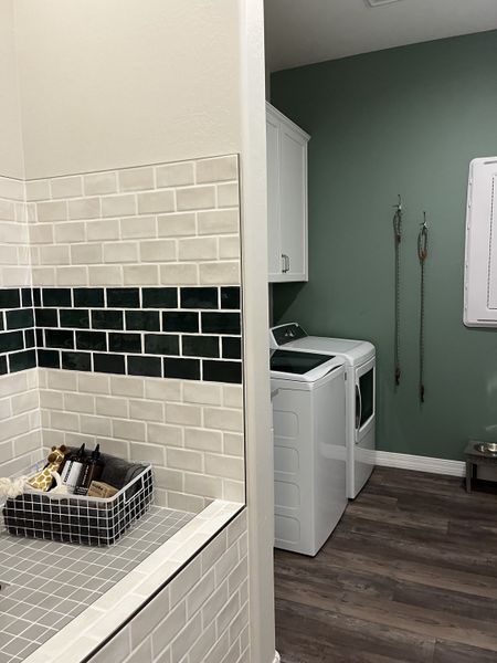 A chic laundry room with a tiled counter, white cabinetry, and green walls. Perfect for efficient home tasks.
