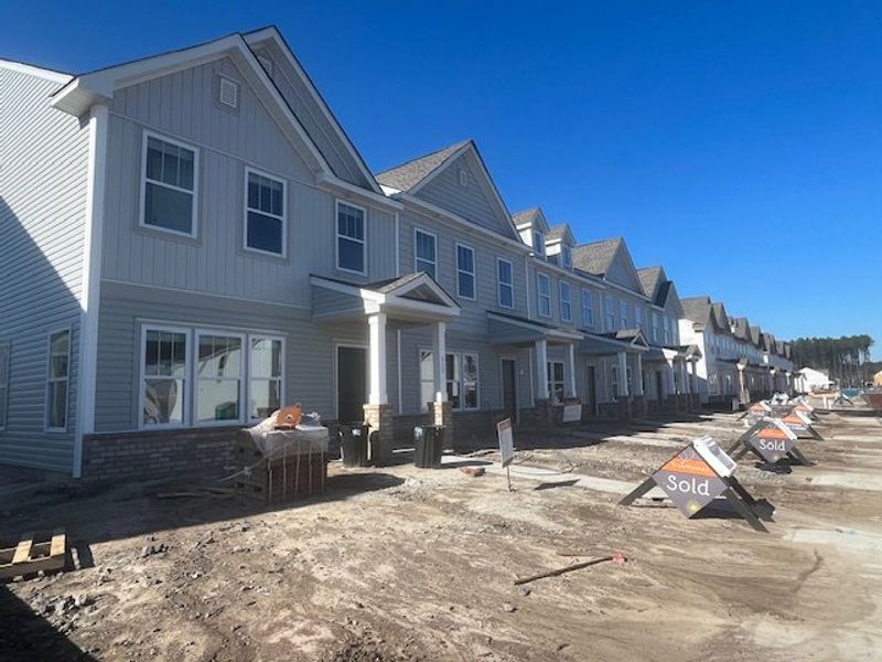 Charming row of modern townhomes with pitched roofs in North Creek at Nexton by True Homes (Summerville, SC).