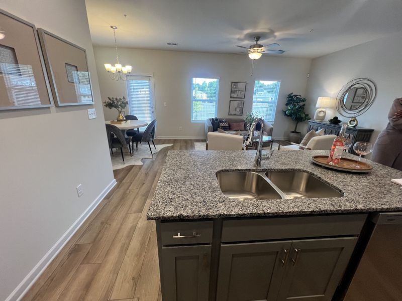 An open-concept living space with a granite kitchen island, stylish dining area, and cozy seating, filled with natural light.
