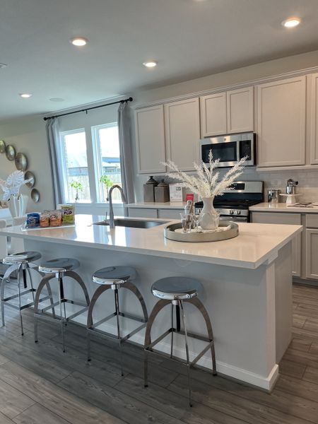 A modern kitchen with sleek cabinetry, stainless appliances, and a spacious island adorned with chic decor.
