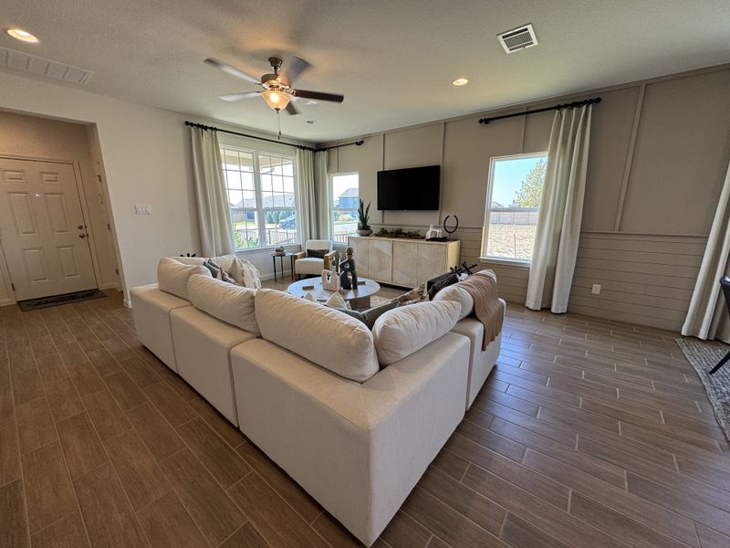 A cozy living room featuring a large sectional sofa, wood floors, and large windows with natural light.