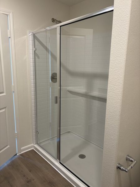 A modern shower with sleek glass doors, white tiles, and stylish fixtures, set against a light and airy bathroom atmosphere.