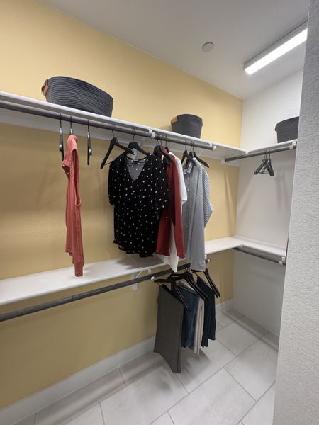 A spacious walk-in closet with neatly arranged clothes and ample shelving under bright illumination.