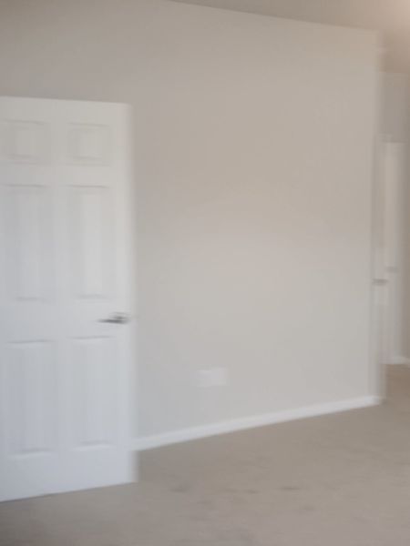 A spacious room with neutral walls, plush carpet, and white doors, offering a blank canvas for personalization.