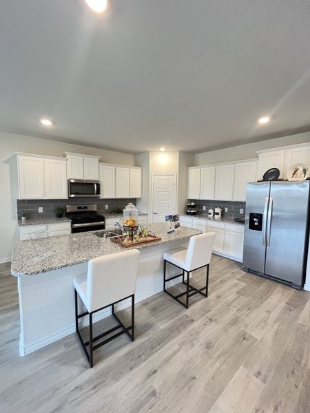 A modern kitchen with sleek granite countertops, white cabinetry, and contemporary appliances. A modern kitchen with sleek granite countertops, white cabinetry, and contemporary appliances.
