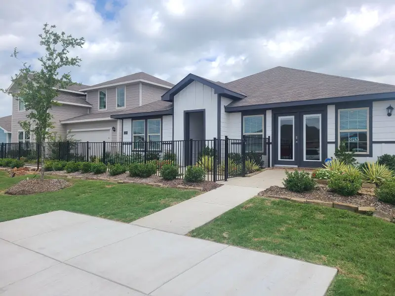 A modern two-story home with a manicured lawn and fence in Ranger Crossing by D.R. Horton (Princeton, TX).