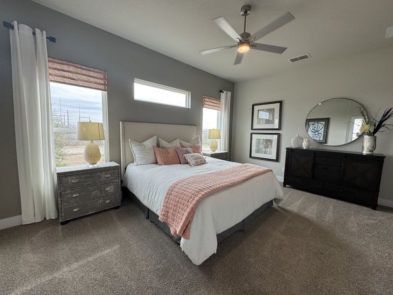 A cozy bedroom featuring a stylish bed, elegant dresser, modern fan, and tasteful decor accents. A cozy bedroom featuring a stylish bed, elegant dresser, modern fan, and tasteful decor accents.