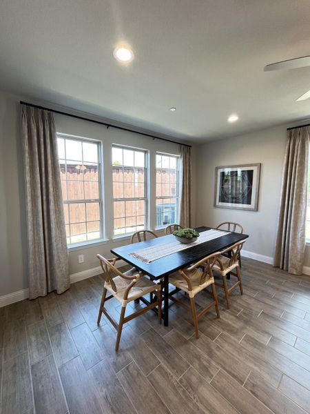 A bright dining room with wood flooring, a sleek black table, and natural light streaming through large windows. A bright dining room with wood flooring, a sleek black table, and natural light streaming through large windows.