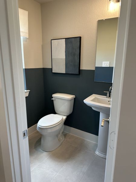 A modern bathroom featuring a pedestal sink, blue accent wall, and stylish artwork. A modern bathroom featuring a pedestal sink, blue accent wall, and stylish artwork.