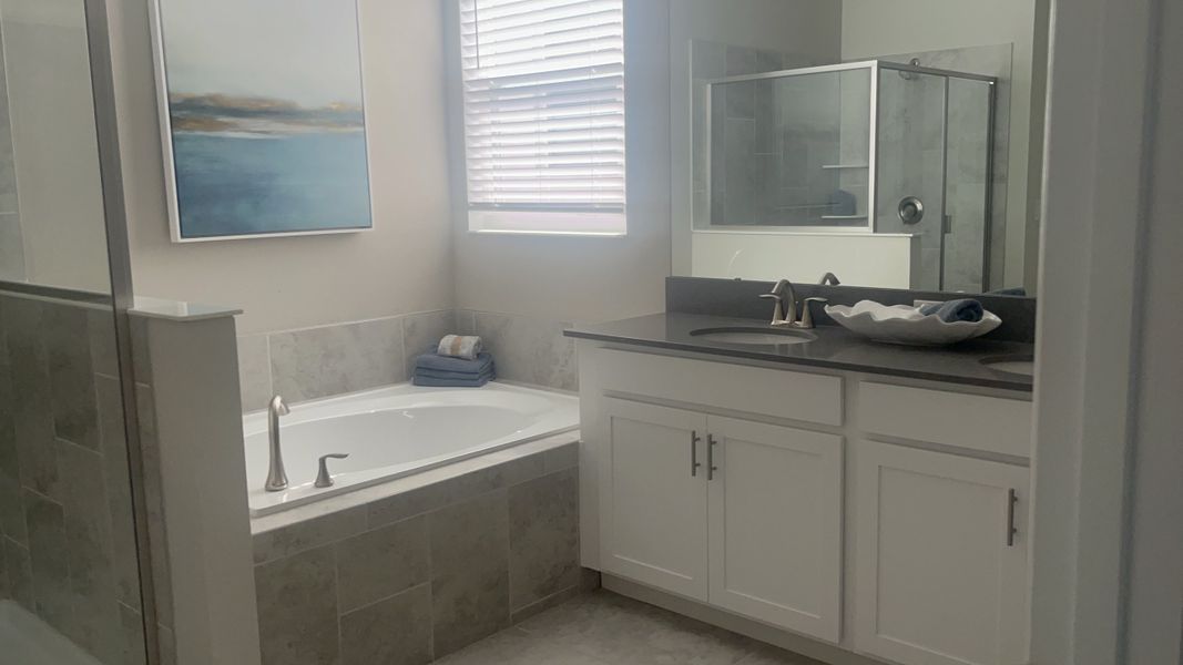 A serene bathroom with a luxurious soaking tub, sleek glass shower, and elegant white cabinetry.