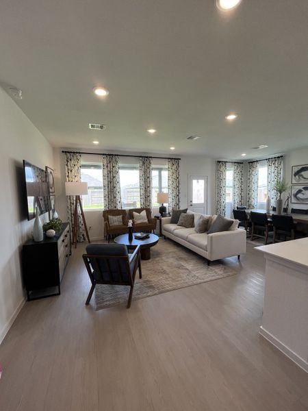 A modern living room with a comfy sofa, elegant decor, and ample natural light streaming through patterned curtains.