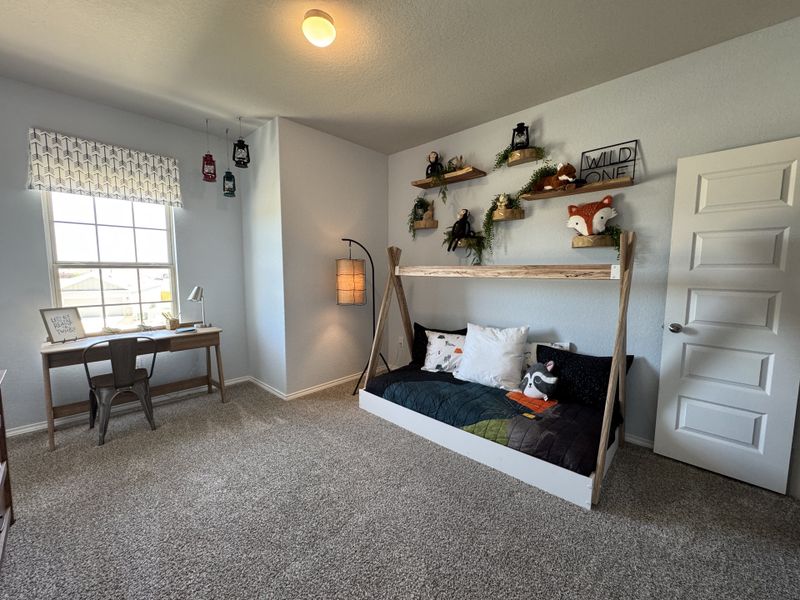 A cozy bedroom with a desk, playful decor, and a daybed adorned with decorative animal cushions and whimsical lanterns.
