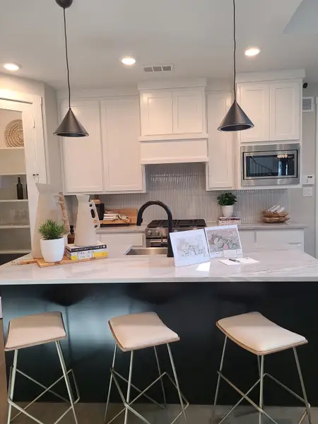 A modern kitchen with sleek white cabinetry, pendant lighting, and a chic island with stylish stools.