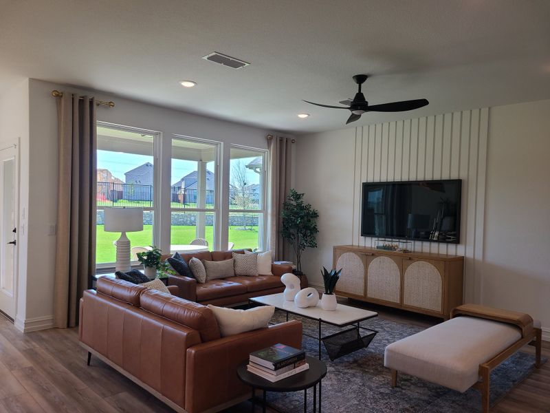 A modern living room featuring leather sofas, a wall-mounted TV, and a large window offering a lush backyard view. A modern living room featuring leather sofas, a wall-mounted TV, and a large window offering a lush backyard view.