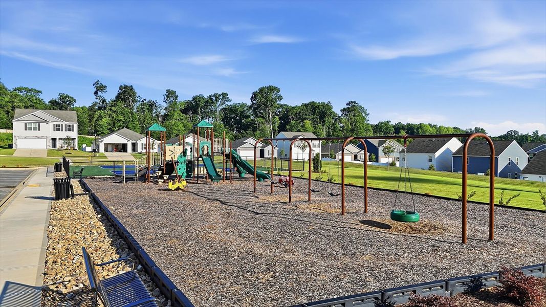 Neighborhood playground with green slides, a swing set, and a nearby community clubhouse at Harrier Point in Woodruff, SC