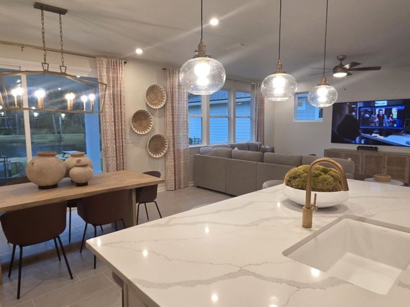 A modern kitchen with marble countertops, stylish pendant lighting, and an open layout leading to a cozy living area.