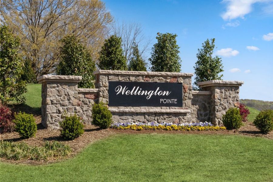Entrance to the Wellington Pointe Executive Series community in Monroe, NC, featuring signage and landscaping (Image 1). Entrance to the Wellington Pointe Executive Series community in Monroe, NC, featuring signage and landscaping (Image 1).