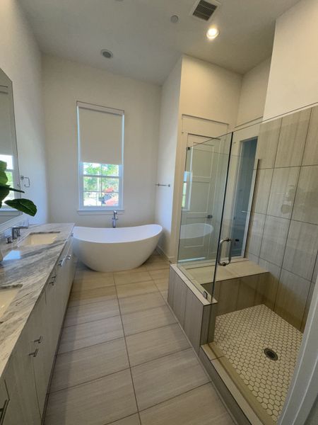 A bright bathroom featuring a freestanding tub, dual sinks on a marble vanity, and a sleek glass-enclosed shower. A bright bathroom featuring a freestanding tub, dual sinks on a marble vanity, and a sleek glass-enclosed shower.