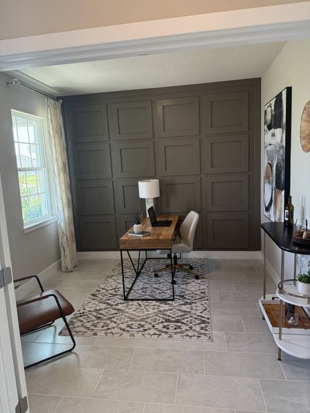 A chic home office with a paneled accent wall, rustic wood desk, and elegant decor. A chic home office with a paneled accent wall, rustic wood desk, and elegant decor.