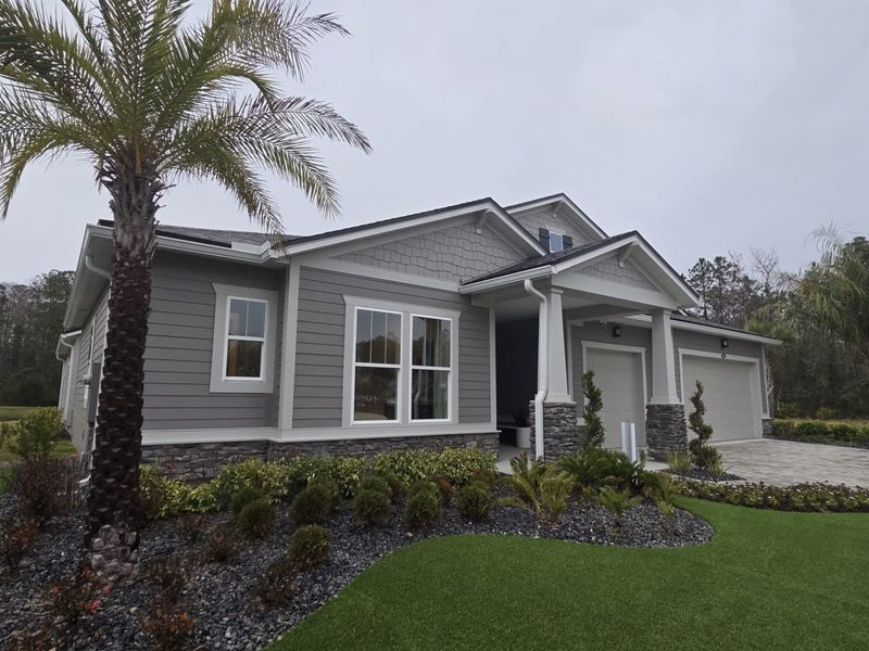 A modern gray home with stone accents and manicured lawn in RiverTown - Ravines by Mattamy Homes (St. Johns, FL).