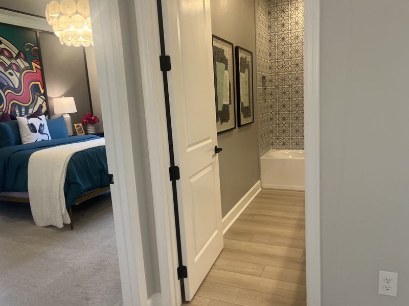 A chic bedroom with vibrant art, a plush blue bed, and a cozy bath area with geometric tiles and modern decor. A chic bedroom with vibrant art, a plush blue bed, and a cozy bath area with geometric tiles and modern decor.